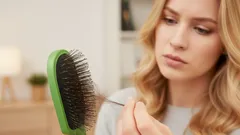 Žena kontroluje ztracené vlasy na kartáči, problém s vypadáváním vlasů.